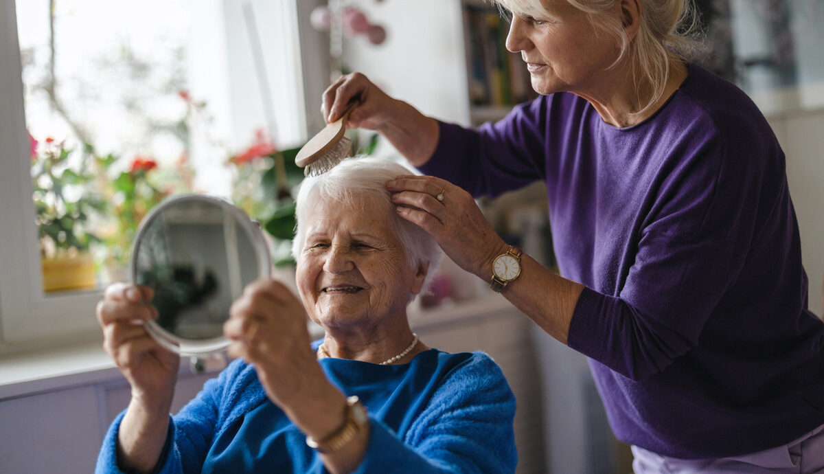 personal care worker brushing the hair of an older woman