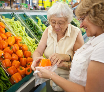 aged care volunter helping older woman with groceries